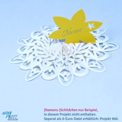 Plottervorlage für eine dekorative Blume als besondere Platzkarte - hier in Weiß mit einem stehenden gelben Namensschild auf einem hellblauen Hintergrund liegend mit dem Logo von ARNi-Plott.
