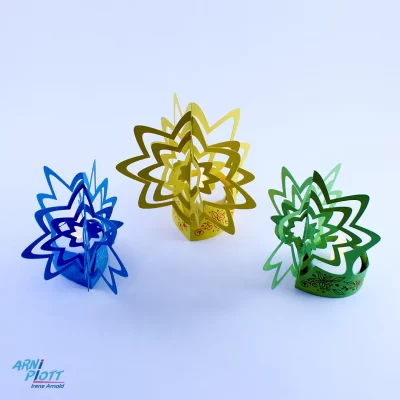 3 Blumen-Aufsteller in Blau, Gelb und Grün mit einem LED-Teelicht. Die Blumen haben einen 3D-Effekt und schwingen bei einem Luftzug. Besondere Tischdkeo nach einer Plotterdatei von ARNi-Plott.
